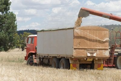 grain loading onto a farm truck from a header with a cloudy sky